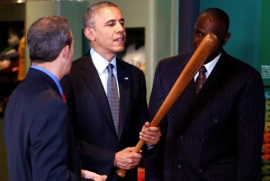 U.S. President Barack Obama holds a Babe Ruth bat as he tours the National Baseball Hall of Fame with Hall of Fame President Jeff Idelson (L) and former player Andre Dawson (R), in Cooperstown, New York, May 22, 2014. Obama is highlighting the tourism industry during his visit to the museum. Robinson was the first African American player in Major League Baseball. REUTERS/Jonathan Ernst (UNITED STATES - Tags: POLITICS SPORT BASEBALL)