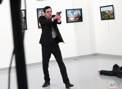 A man identified as Mevlut Mert Altintas gestures after shooting Andrei Karlov, the Russian Ambassador to Turkey, on the floor, at a photo gallery in Ankara, Turkey, Monday, Dec. 19, 2016. (AP Photo/Burhan Ozbilici)  
